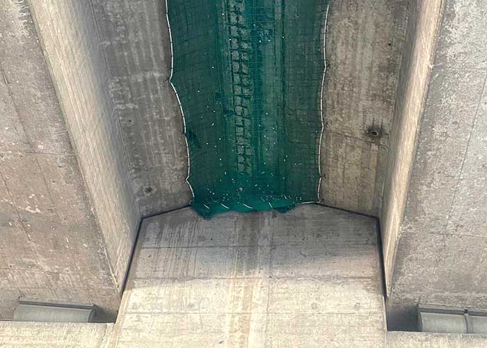 Ein grünes Sicherheitsnetz von Endriagonets ist unter einer Brücke befestigt